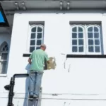 a man painting a house white