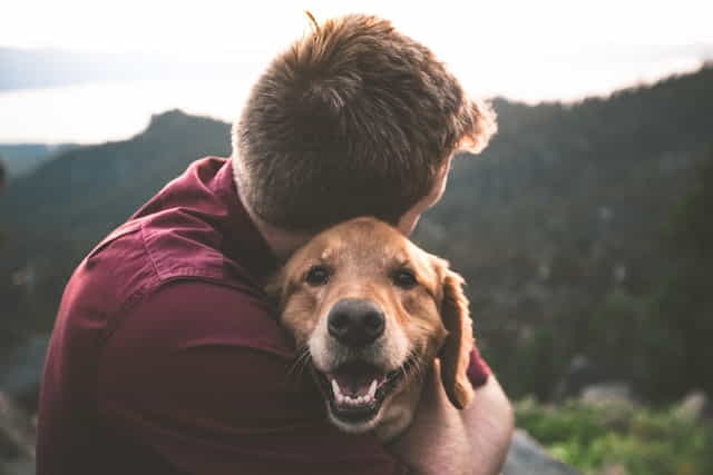 man embracing pet dog
