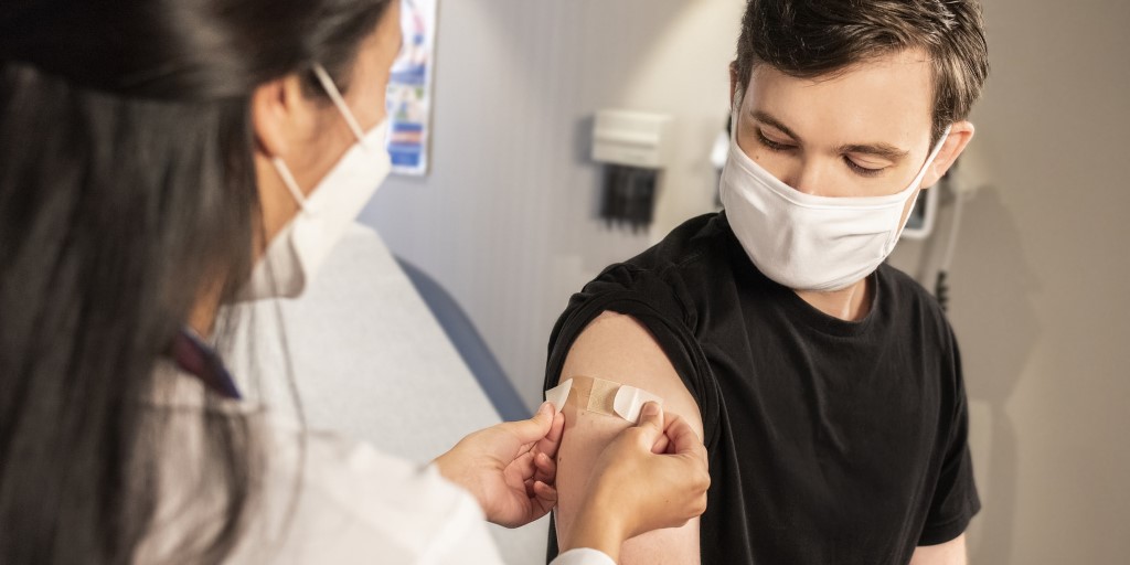 a health care provider places a bandage on the injection site of a patient
