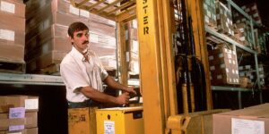 A man driving a fork lift in the warehouse